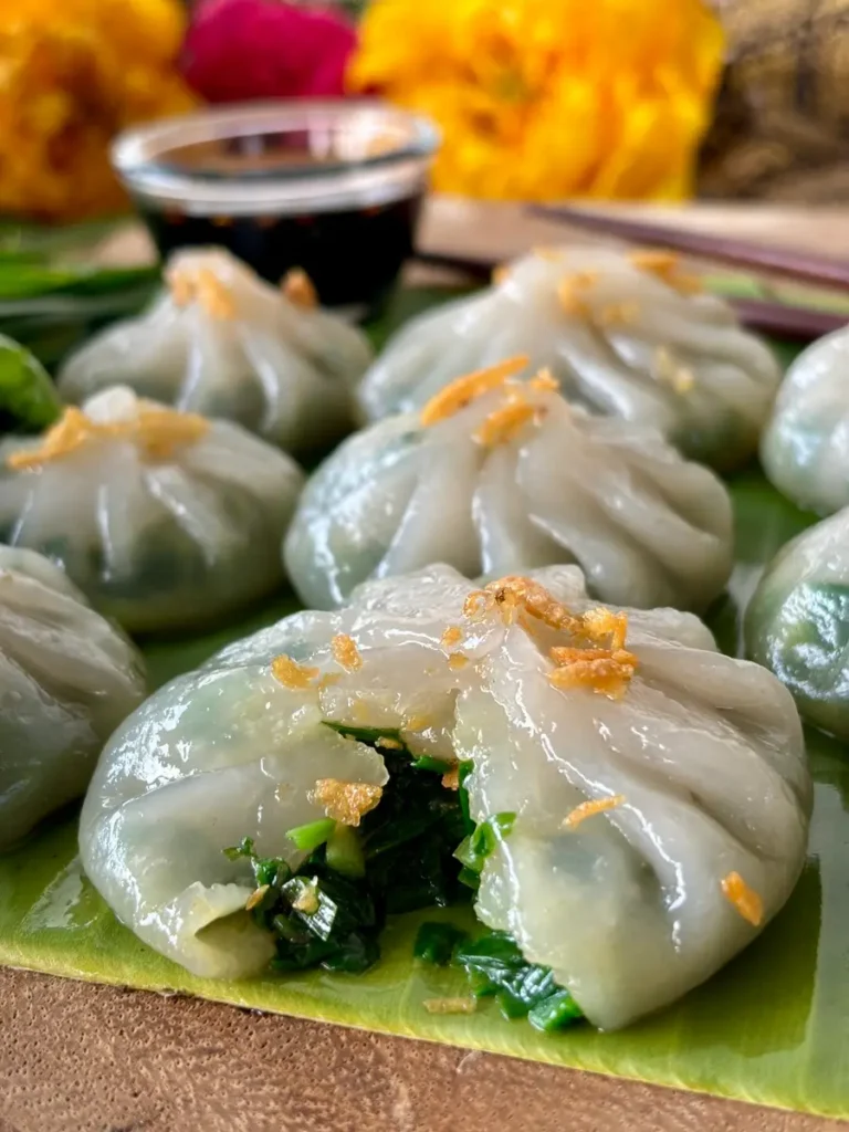 Close-up of steamed Thai chive dumplings, known as Kanom Gui Chai, revealing the green filling.