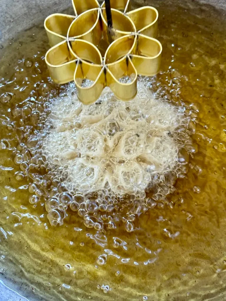 Lotus flour mold releasing cookie in oil.