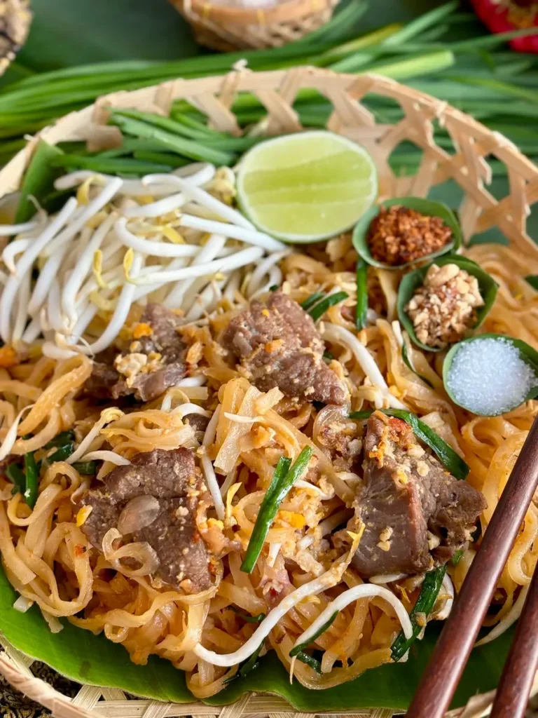 Pad Thai beef with a side of bean sprouts, lime, pepper flakes, peanuts, and sugar.