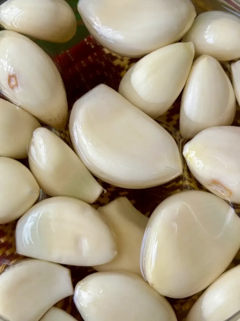 Close-up of Thai pickled garlic cloves immersed in a clear brine.