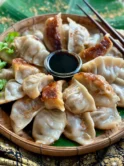 Pork gyoza with sauce on a traditional bamboo-woven dish.