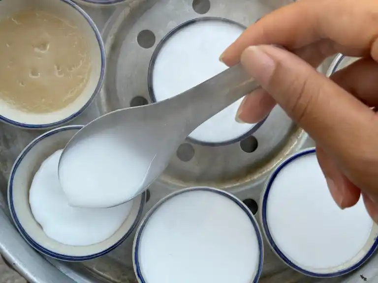 Spooning top layer on bottom layer in ceramic cups.