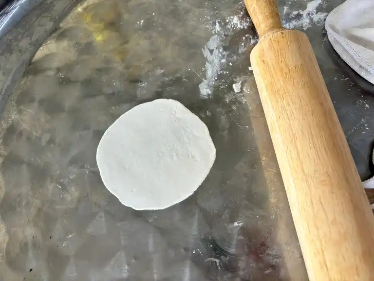 Rolled out dumpling wrapper with rolling pin.