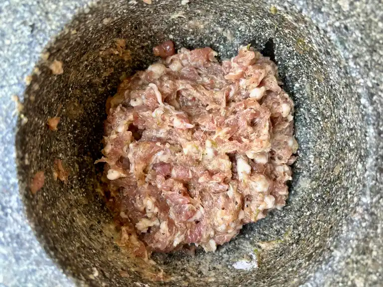 Seasoned ground pork in stone mortar.