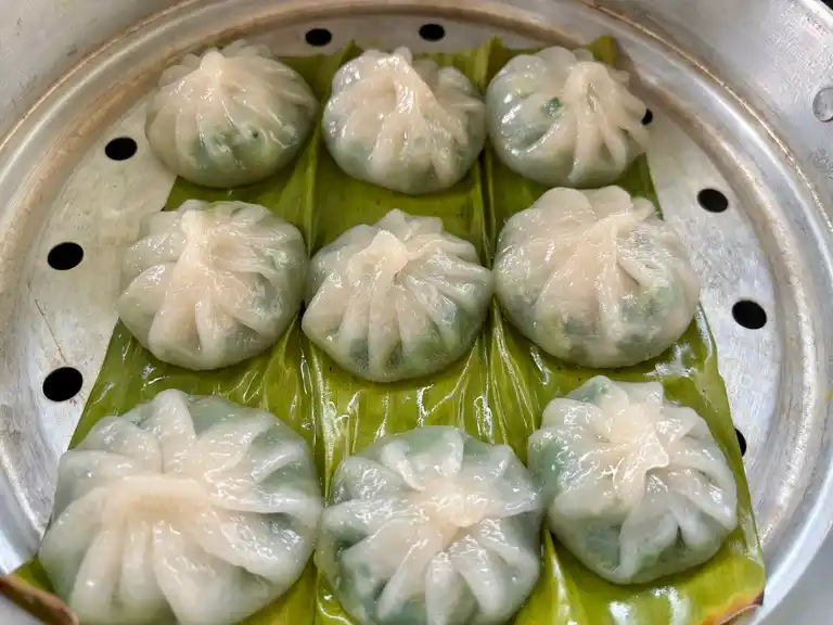 Steamed garlic chive dumplings in a steamer showing the translucent dough.