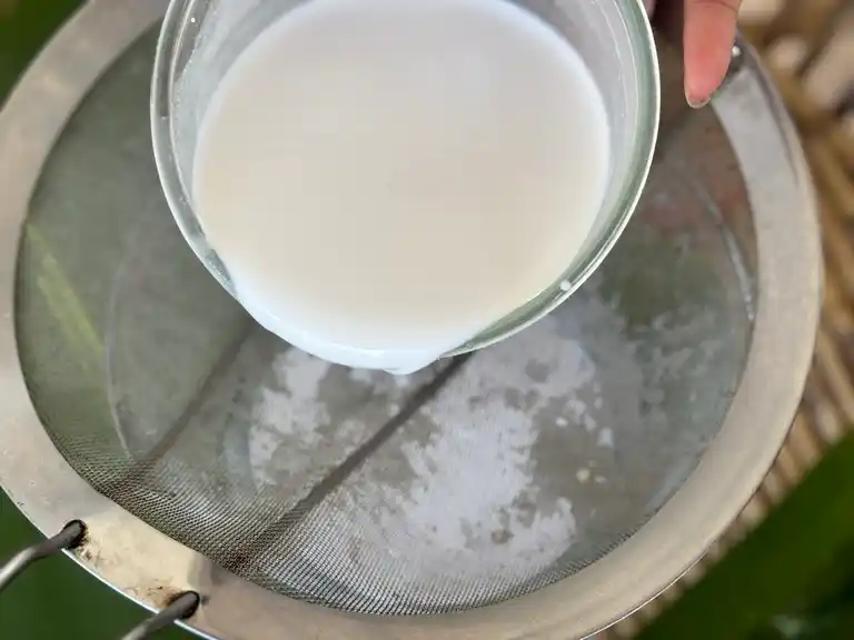 Straining coconut milk with sieve.