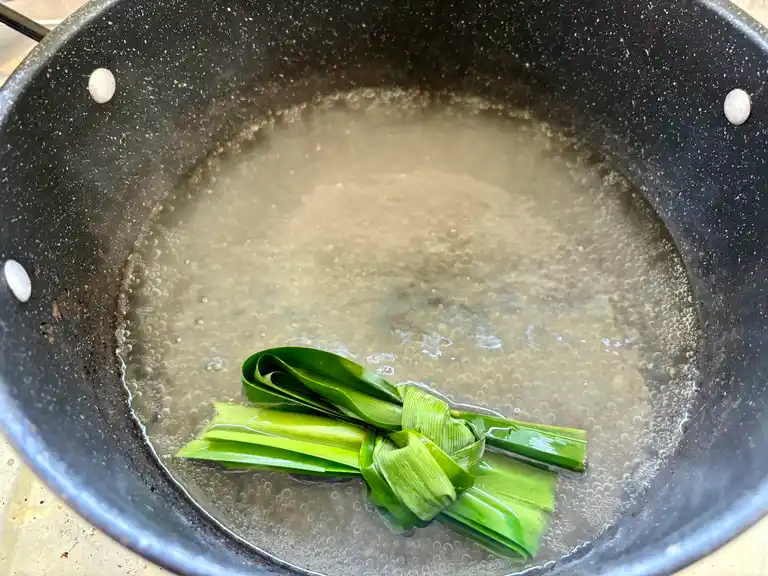 Sugar syrup in a pot with pandan leaf.