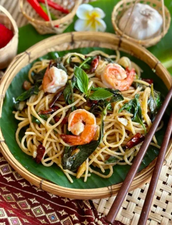 Thai basil pasta with spaghetti and shrimp, served in a bamboo bowl.