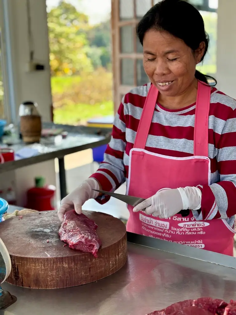 Thai beef vendor slicing beef in her shop.