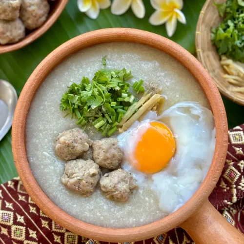 Thai congee, jok rice porridge, with pork meatballs, garnished with green onions and coriander with egg.