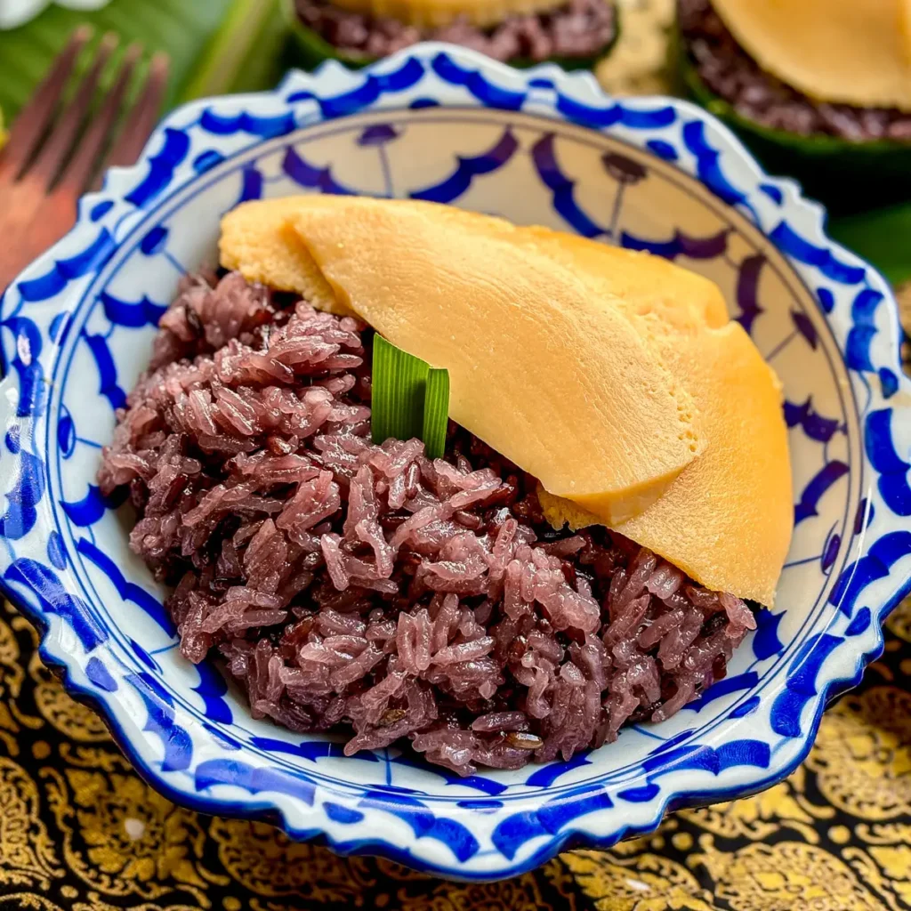 Sweet sticky rice Thai custard, sankaya, served in a blue patterned bowl with a pandan leaf garnish.