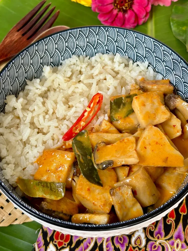 A bowl of vegetarian Thai red curry served with steamed jasmine rice.