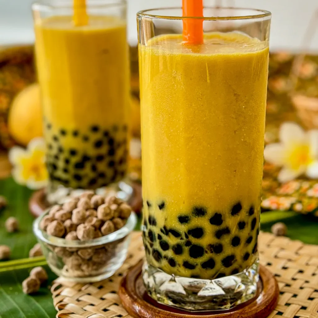 Two glasses of mango bubble tea with visible tapioca pearls.