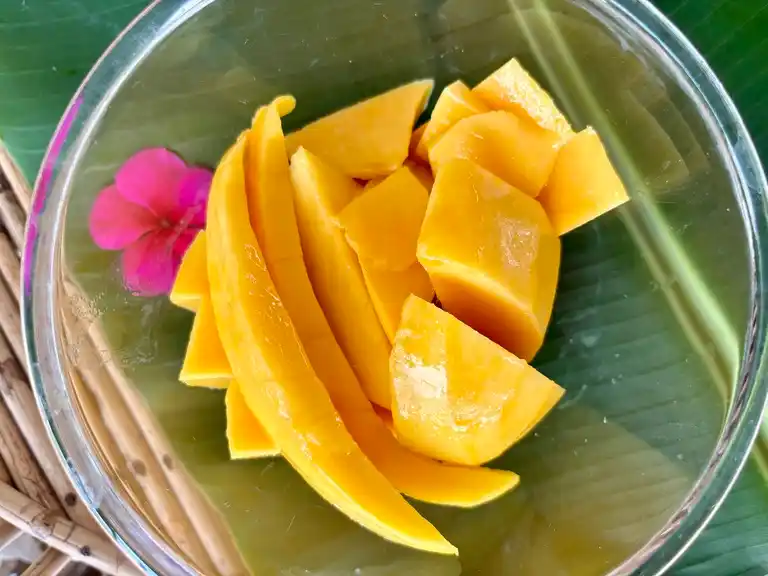 Slices of ripe mango in a clear bowl.