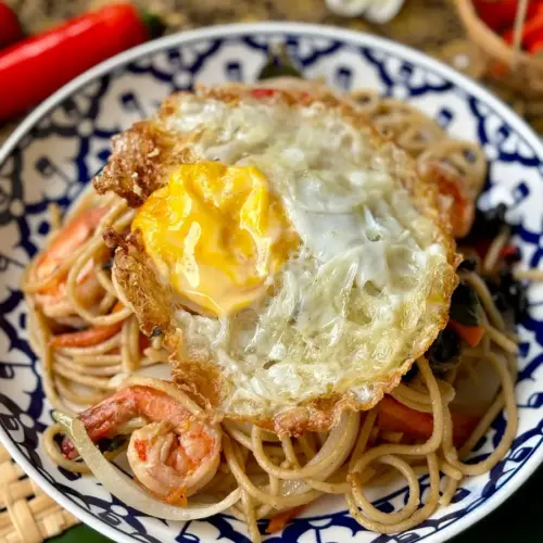 A Thai fried egg served on pasta.