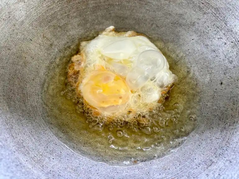 Thai fried egg cooking in a wok.