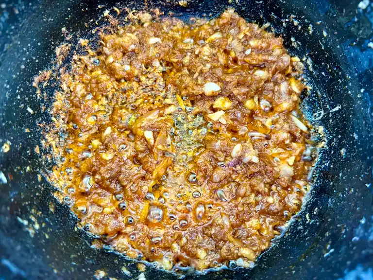 Massaman curry paste with shallots and garlic frying in a pan.