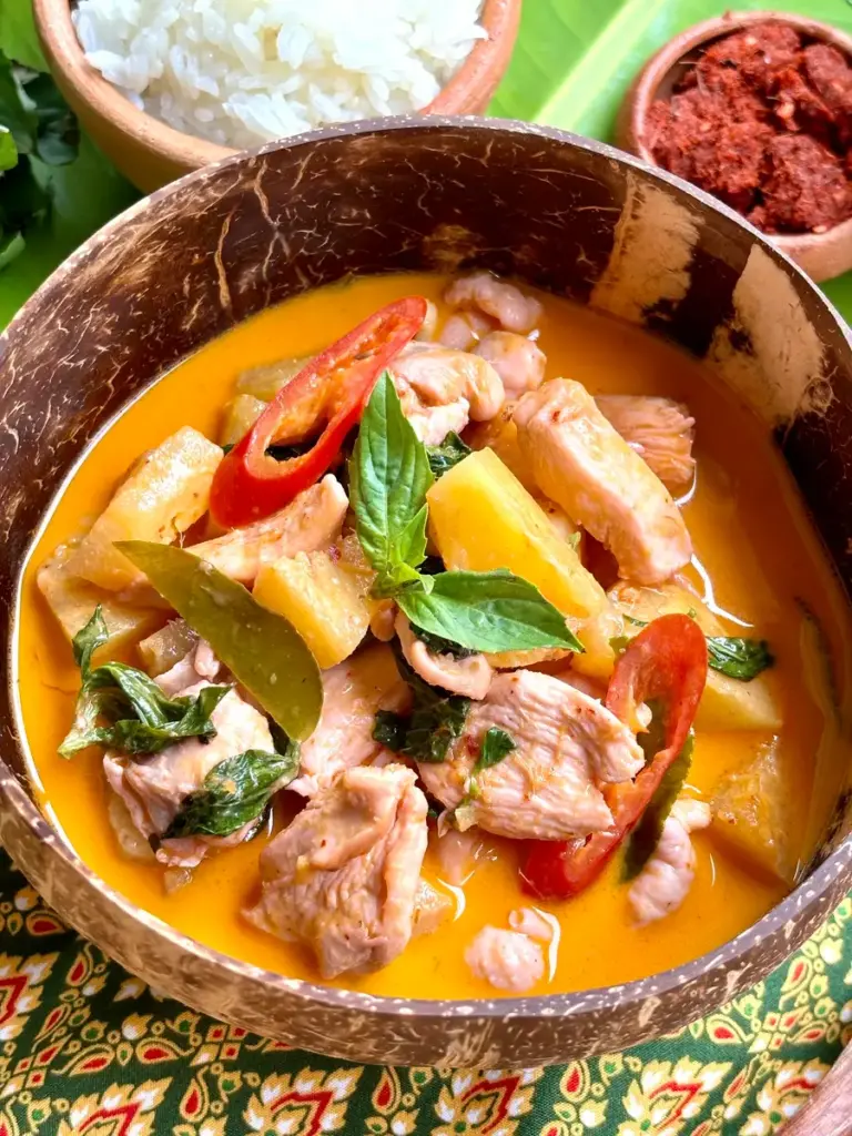 Close-up of Thai pineapple curry chicken, served in a coconut shell.