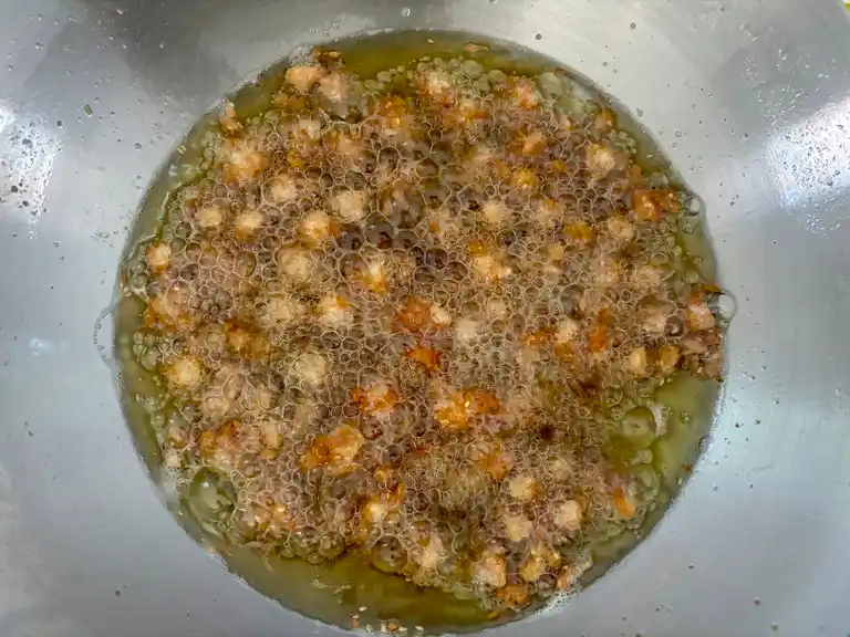 Frying chicken knuckles in a wok pan.