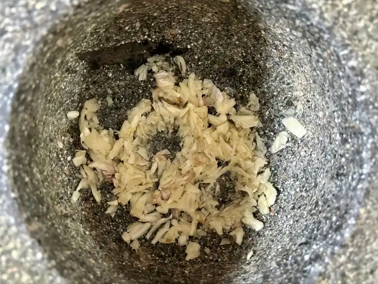 Crushed garlic in a stone mortar.