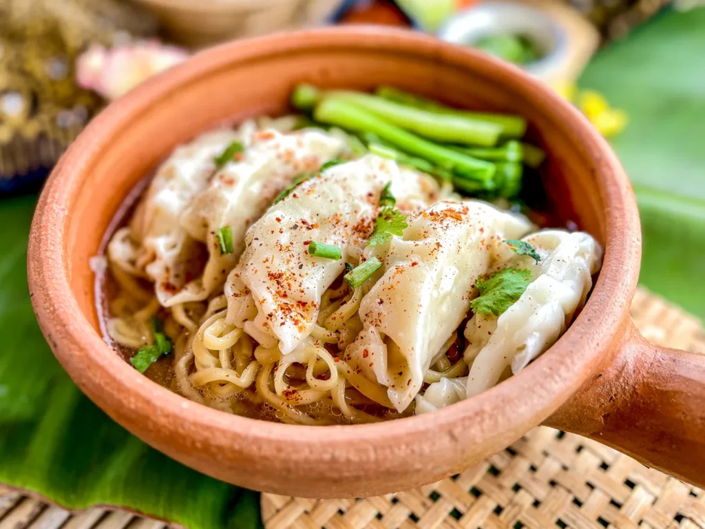Wonton egg noodle soup served in a clay dish.