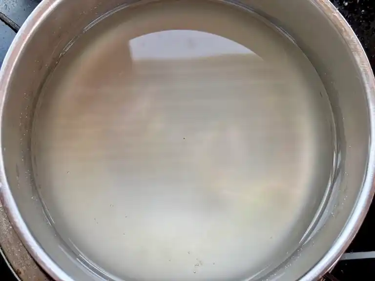 Transparent agar-agar mixture in a plastic container, ready for preparation, placed on a wooden table.