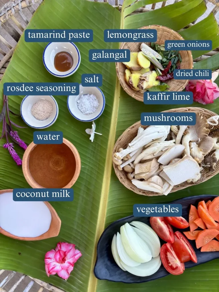 Ingredients for vegetarian Thai mushroom soup spread on a banana leaf, including tamarind paste, coconut milk, mushrooms and spices.