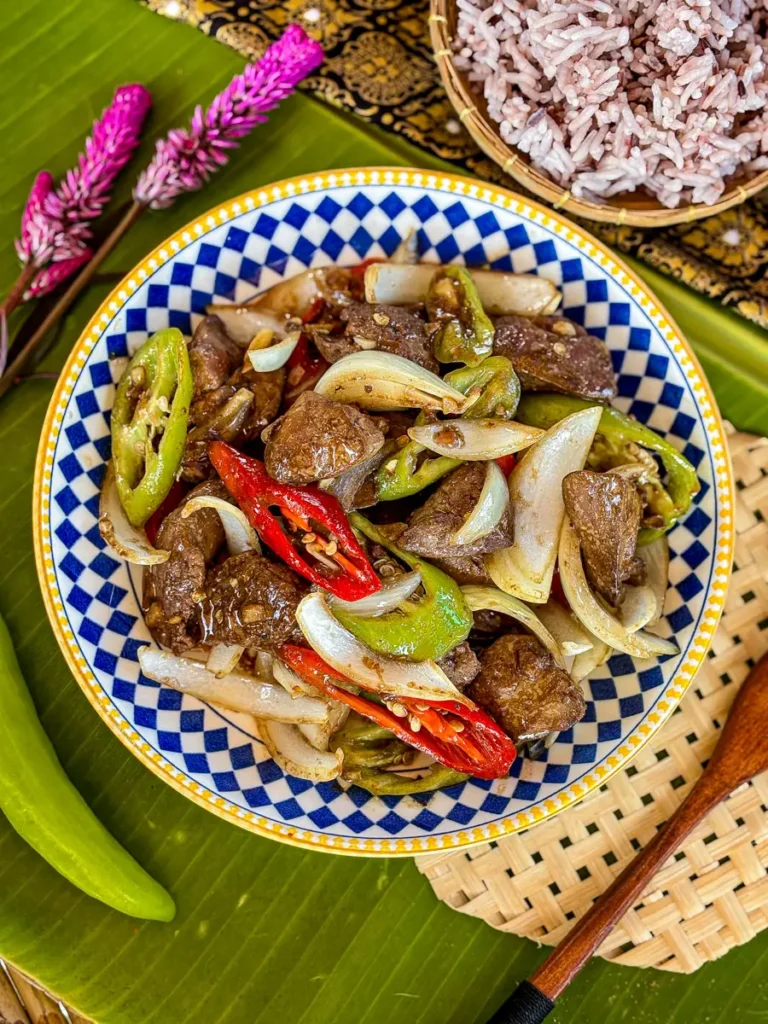 Stir fried chicken liver with chilies and onions served in a decorative blue and white bowl.