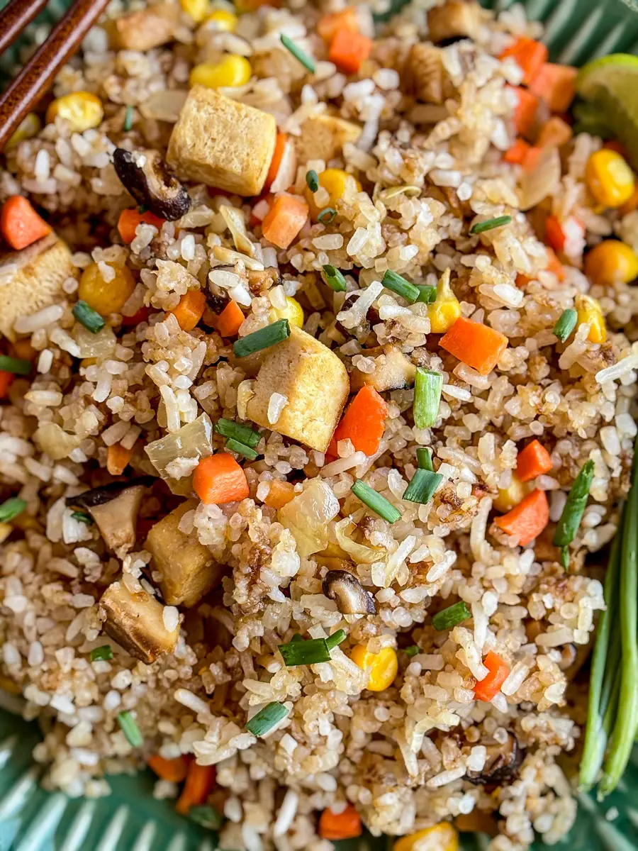 A close-up shot of fried rice with tofu cubes, diced carrots, sweet corn, and shiitake mushrooms.