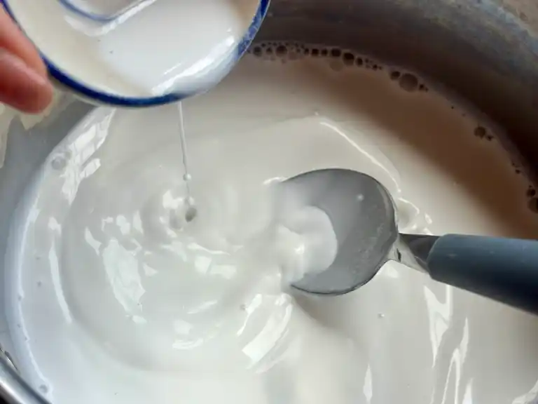 Rice flour mixture being poured into thick coconut milk.