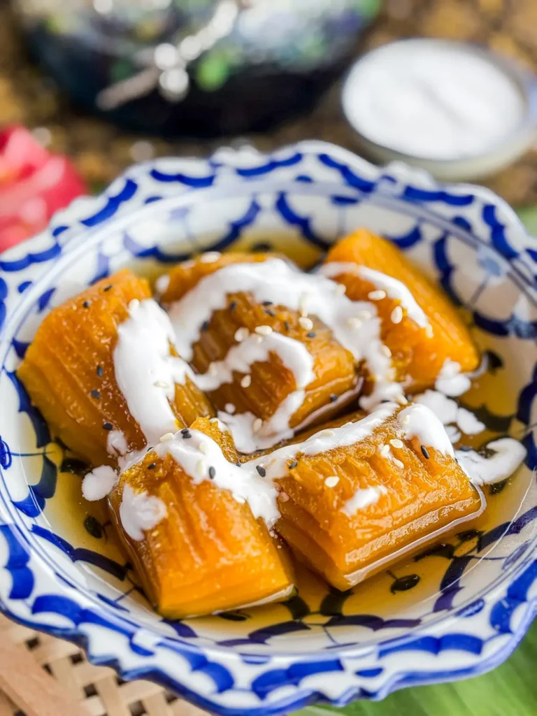 Traditional Thai dessert of soft pumpkin in syrup, served in a decorative bowl with coconut milk on top.