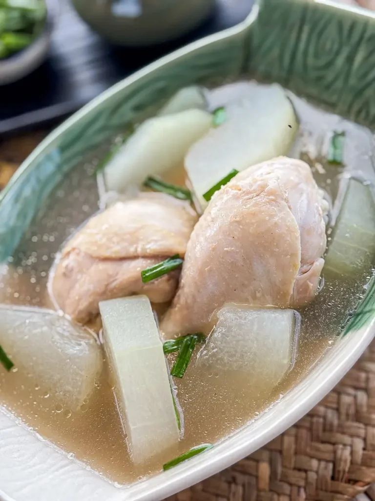First floor of healthy winter Thai winter soup with tender chicken chopsticks and translucent melon in a light and tasty broth.