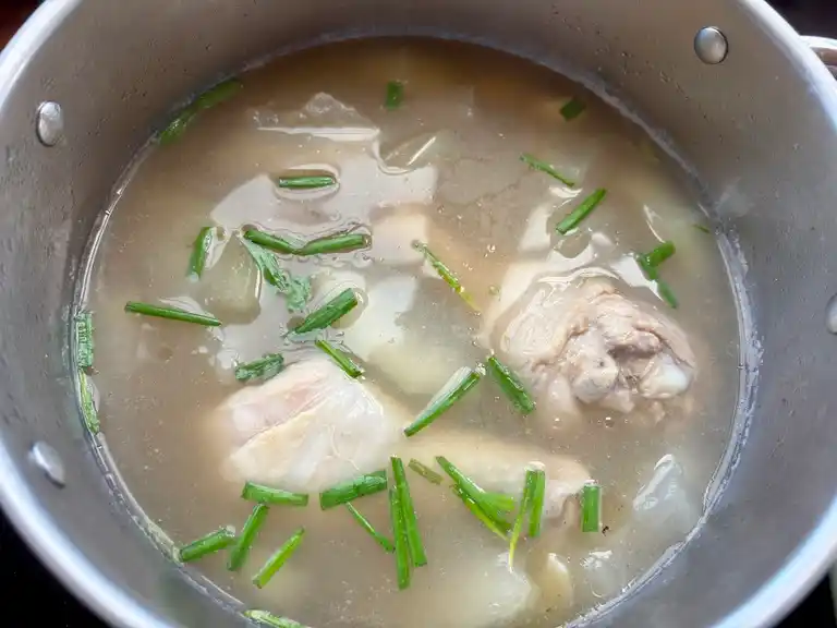 Thai winter melon soup finished with chicken chicken with green onions chopped in a pot.