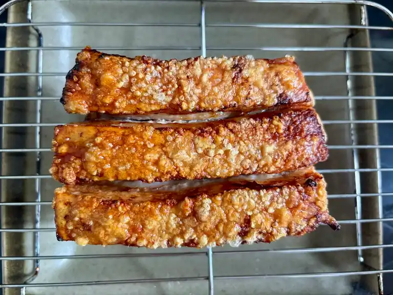 Crispy pork belly resting on a cooling rack after air frying.