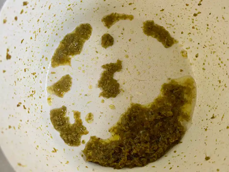 Green curry paste sizzling in oil inside a pot.