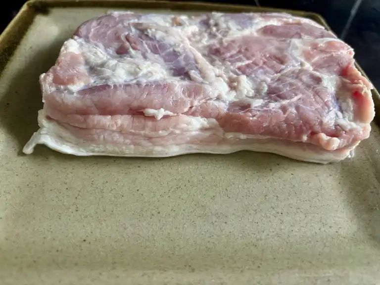 Raw pork belly slab soaking in vinegar.