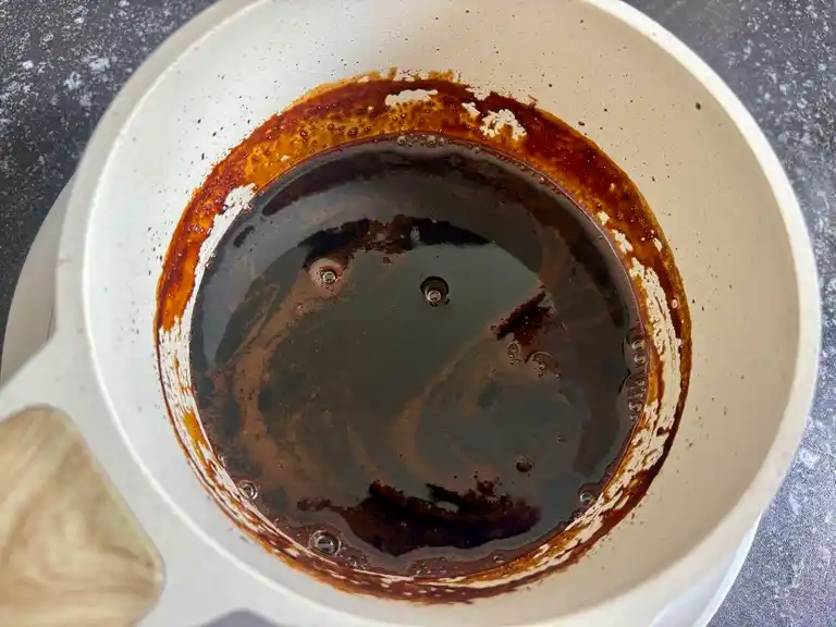 Finished crispy pork belly dipping sauce in a saucepan, smooth and glossy.