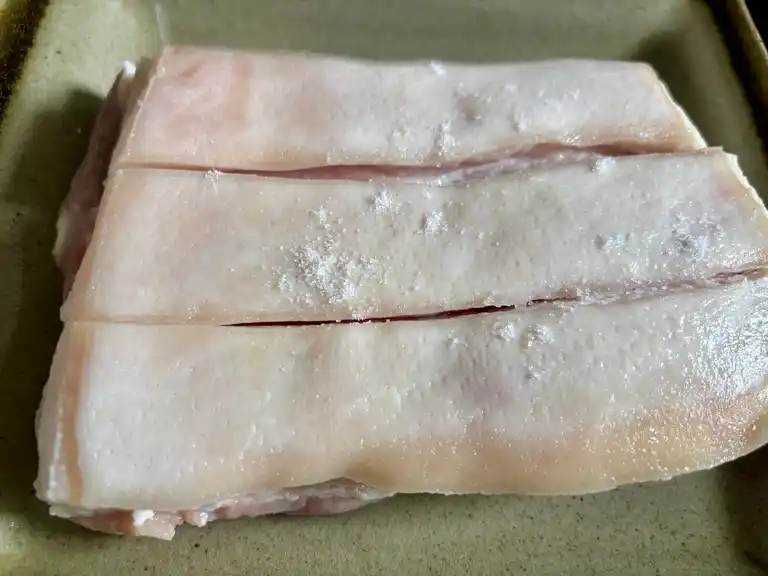 Pork belly skin sprinkled with salt to draw out moisture.