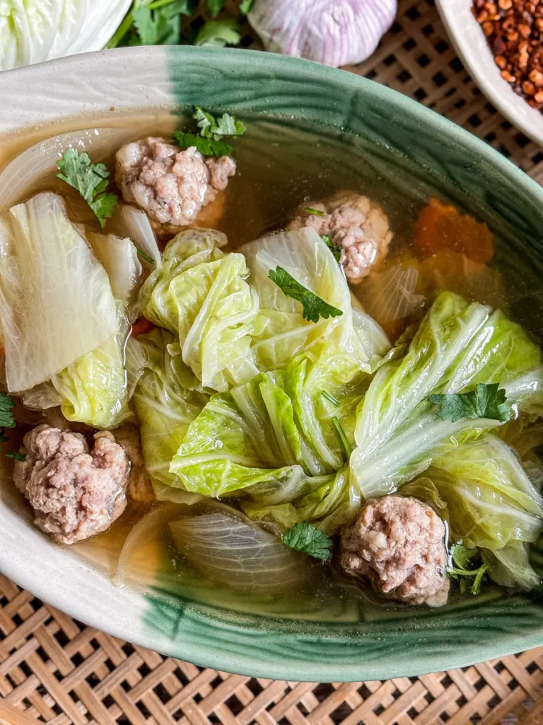 Close-up of Thai cabbage soup with tender cabbage leaves and pork meatballs in a clear savory broth.