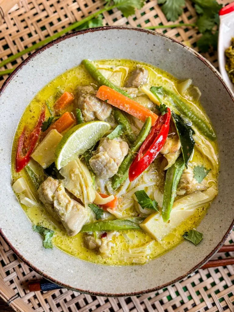 Thai green curry soup with chicken, bamboo shoots, carrots, yard long beans, and kaffir lime leaves in a coconut milk broth.