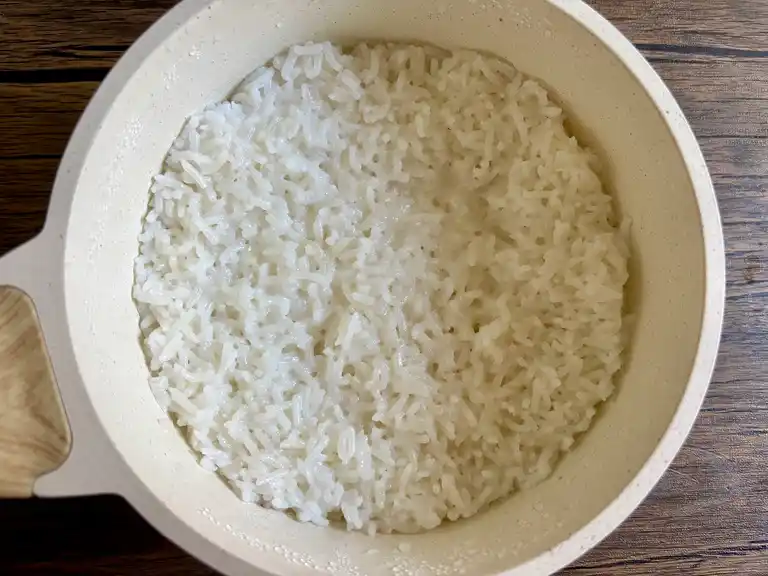 Fluffy coconut rice fully cooked and resting in the pot.