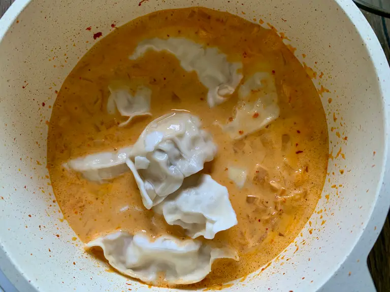 Frozen wontons added to red curry broth.