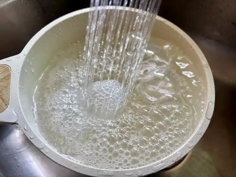 Rinsing jasmine rice under water in a pot to remove excess starch.
