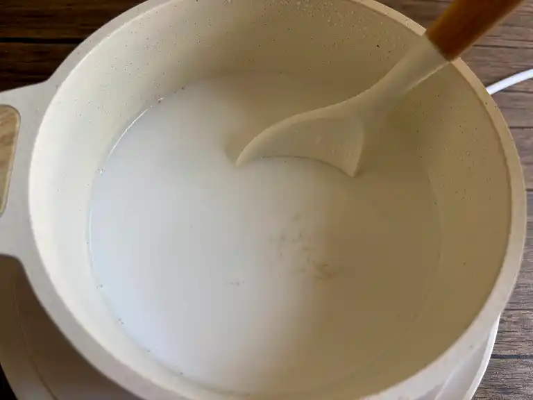 Coconut milk starting to simmer gently in the pot.