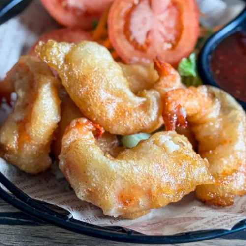 Close-up of golden fried tempura shrimp with crunchy coating on parchment paper