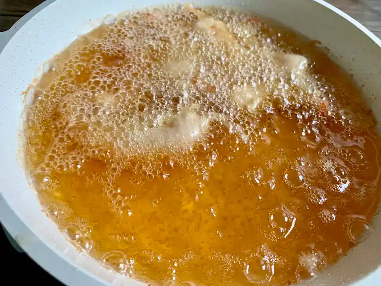 Shrimp tempura frying in hot oil until golden and crispy.