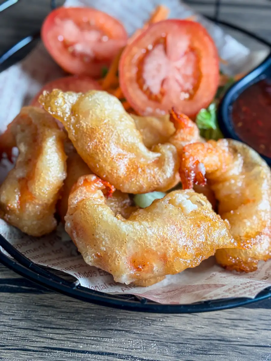 Close-up of golden fried tempura shrimp with crunchy coating on parchment paper