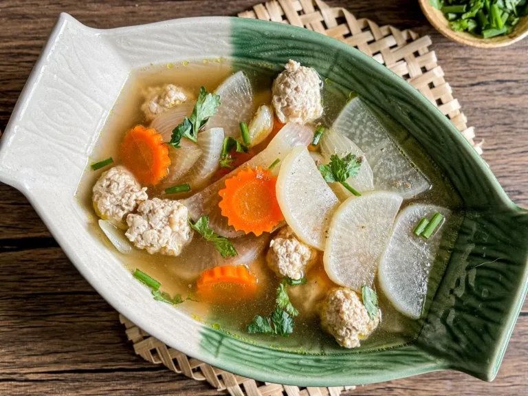 Thai pork daikon soup in a green ceramic bowl, featuring tender radish slices and juicy pork meatballs.