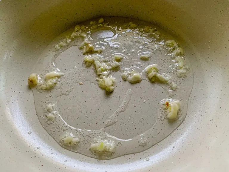 Chopped garlic sizzling in oil in a nonstick skillet.