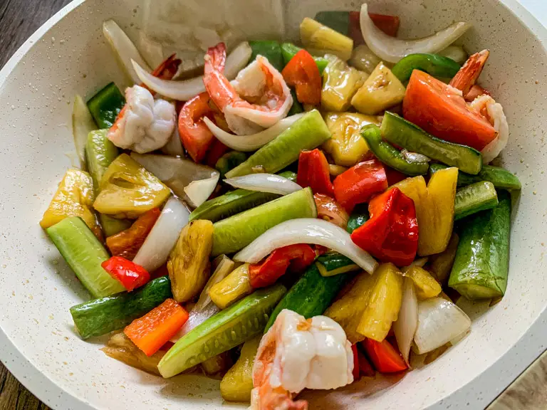 Finished Thai sweet and sour shrimp in a skillet with juicy shrimp, pineapple, bell peppers, and tomatoes, all tossed in sauce.